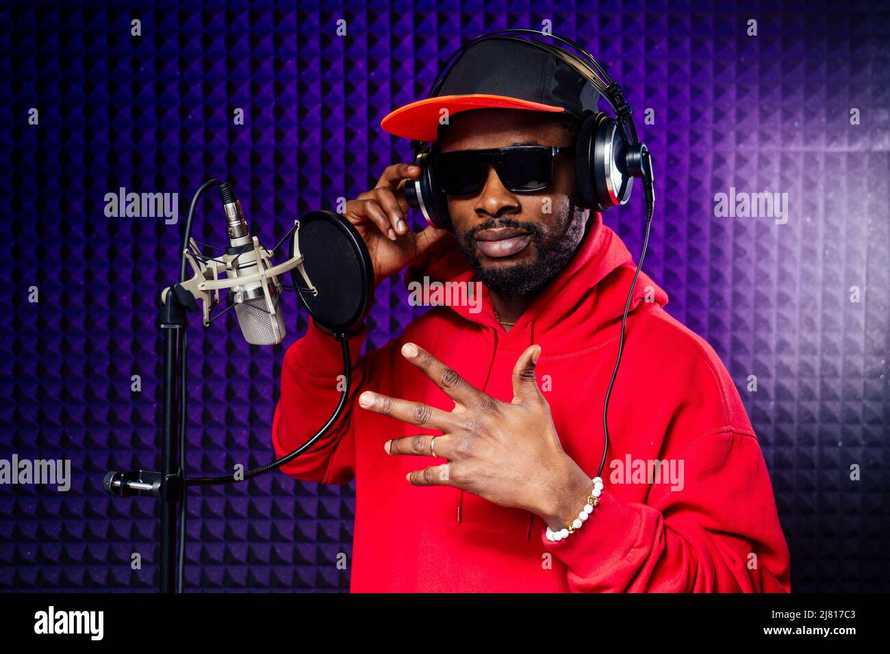 casque afro american man dans une casquette et une capuche lunettes de soleil enregistrant le morceau de hip hop. Banque D'Images