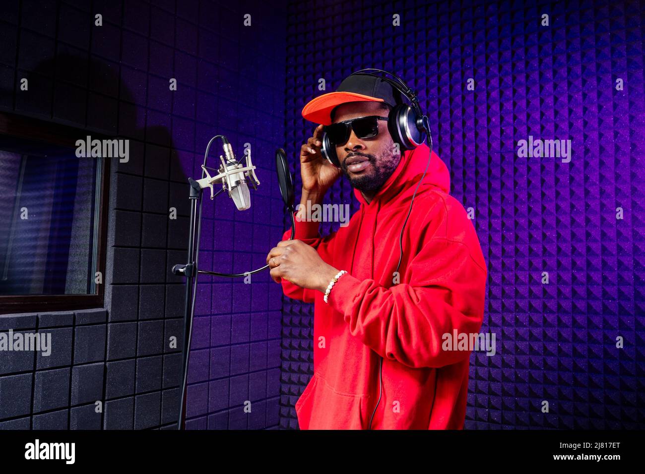 casque afro american man dans une casquette et une capuche lunettes de soleil enregistrant le morceau de hip hop. Banque D'Images