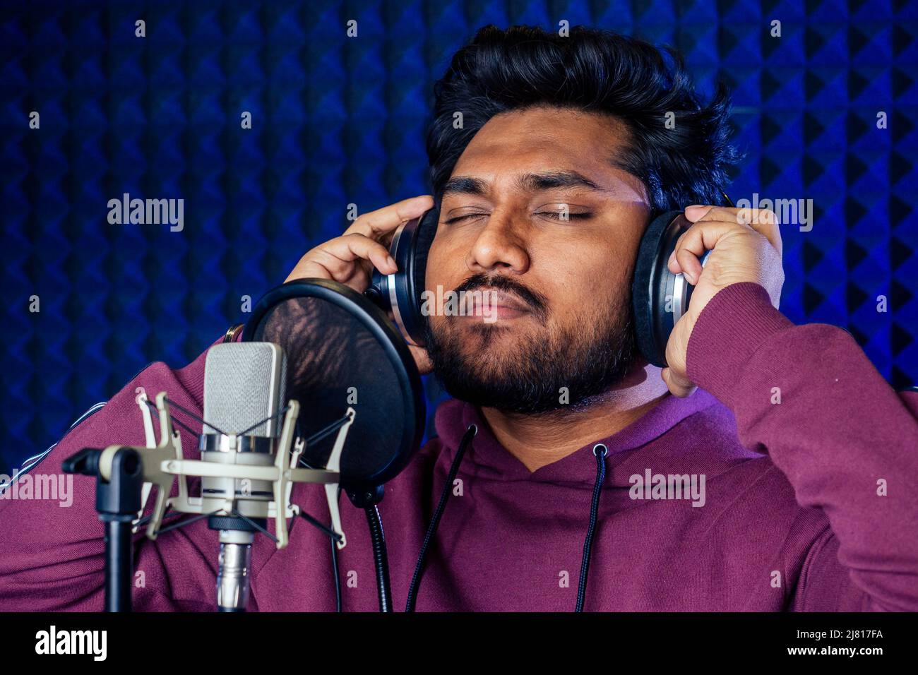 professionnel chant hommes indiens écouteurs son moderne studio violet fond d'enregistrement de chanson. Banque D'Images