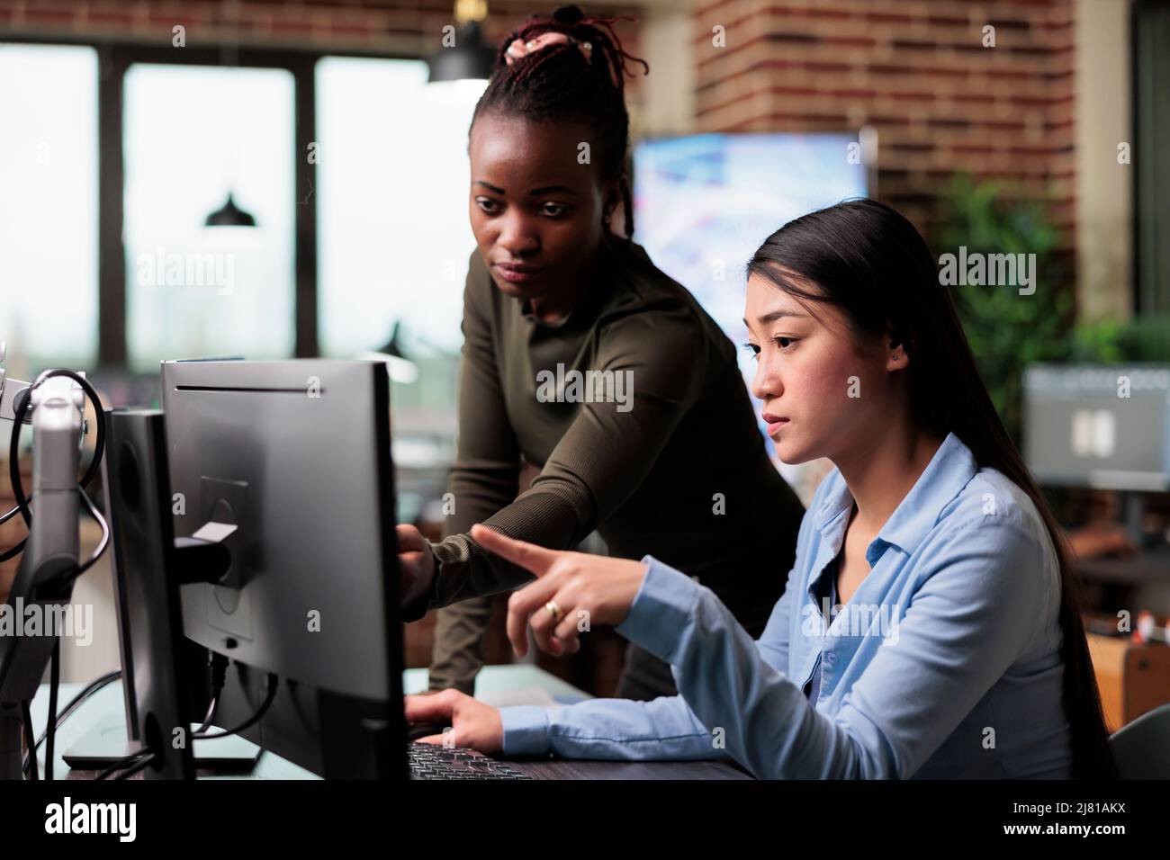 Des employés de bureau créatifs et divers examinent l'avancement du projet 3D tout en résolvant les problèmes graphiques. Les membres de l'équipe multiethnique de l'entreprise travaillent ensemble pour obtenir le meilleur résultat numérique. Banque D'Images