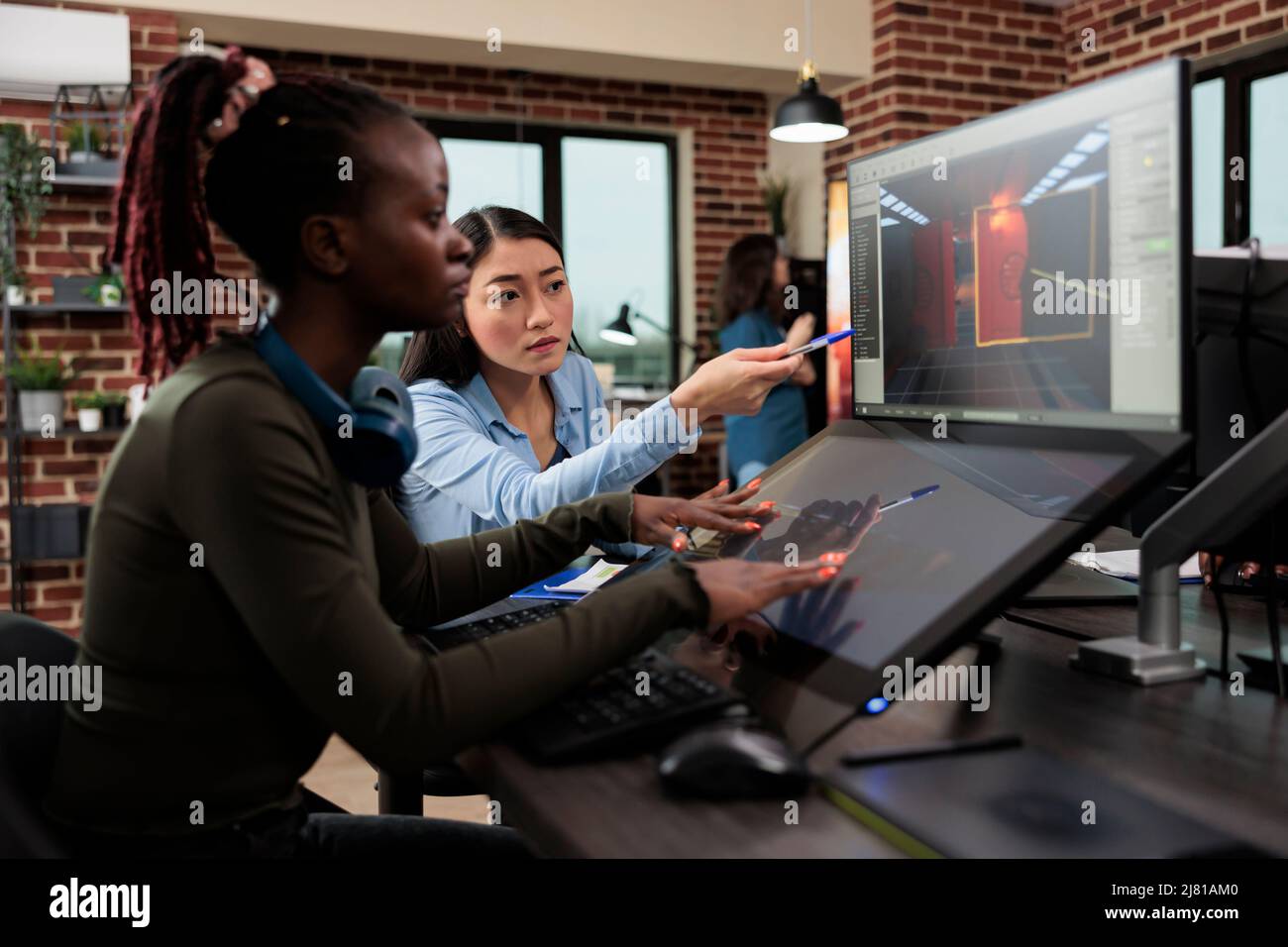 Travailleurs de l'industrie du divertissement interactif numérique travaillant avec CGI. Développement de jeux agences créatives artistes conversant sur la conception de niveau et 3D actifs tout en étant assis dans un espace de travail de bureau. Banque D'Images