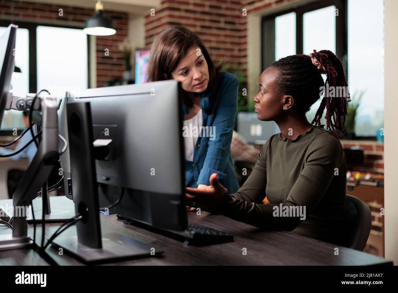 Artiste numérique afro-américain discutant avec le chef d'équipe de logiciels de conception défectueux. Collègues multiethniques dans la conversation sur la technologie de développement graphique et comment l'améliorer. Banque D'Images