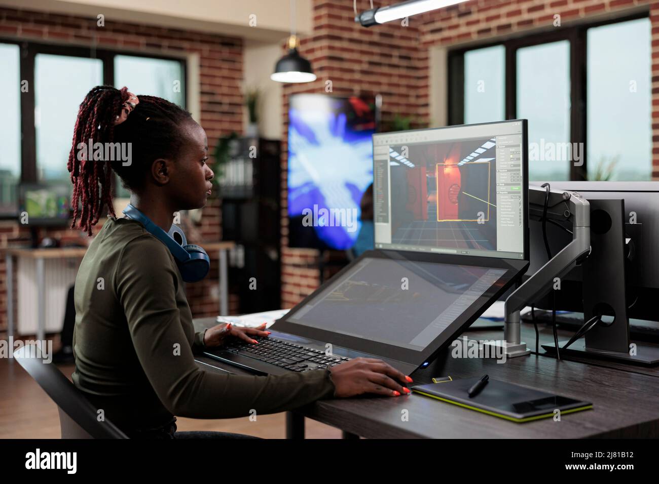L'employé du département de production développe des mécanismes de jeu afin d'atteindre le réalisme. Concepteur de jeux assis dans un espace de travail de bureau tout en travaillant sur l'environnement et les détails de niveau. Banque D'Images