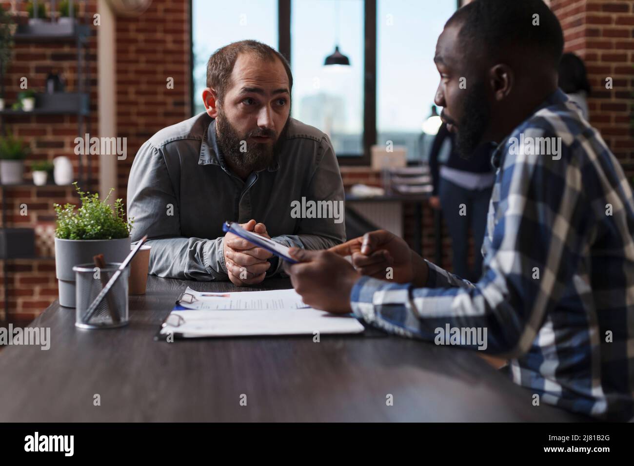 Le directeur général s'entretient avec un homme confiant tout en examinant le CV et en posant des questions sur l'expérience de travail sur le terrain. Homme d'affaires afro-américain présentant un candidat à l'offre d'emploi et de salaire. Banque D'Images