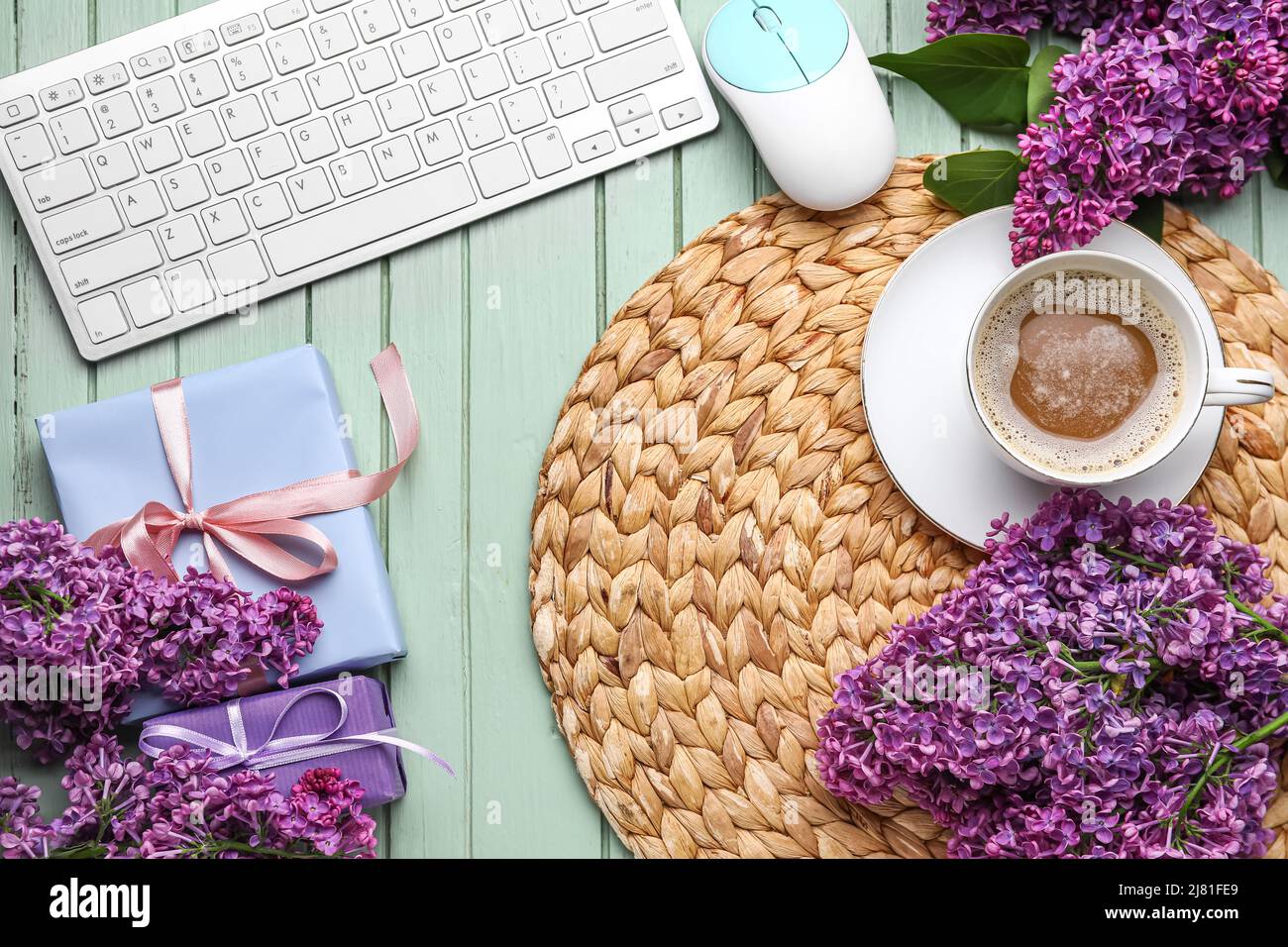 Tasse de café avec fleurs lilas, cadeau, clavier d'ordinateur et souris sur fond de bois vert Banque D'Images