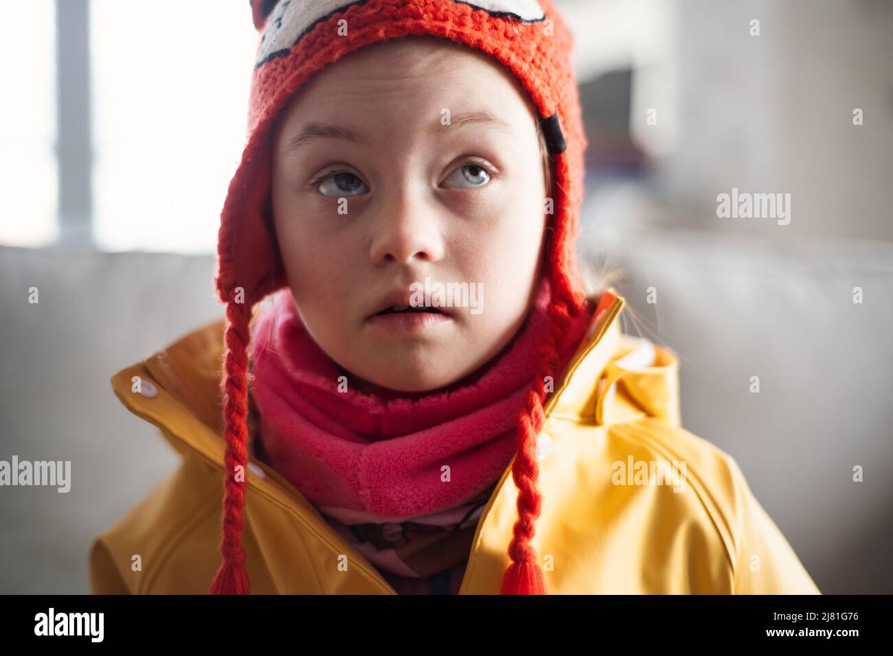 Petite fille avec le syndrome de Down regardant les caméras outoors en hiver contre le mur de brique. Banque D'Images