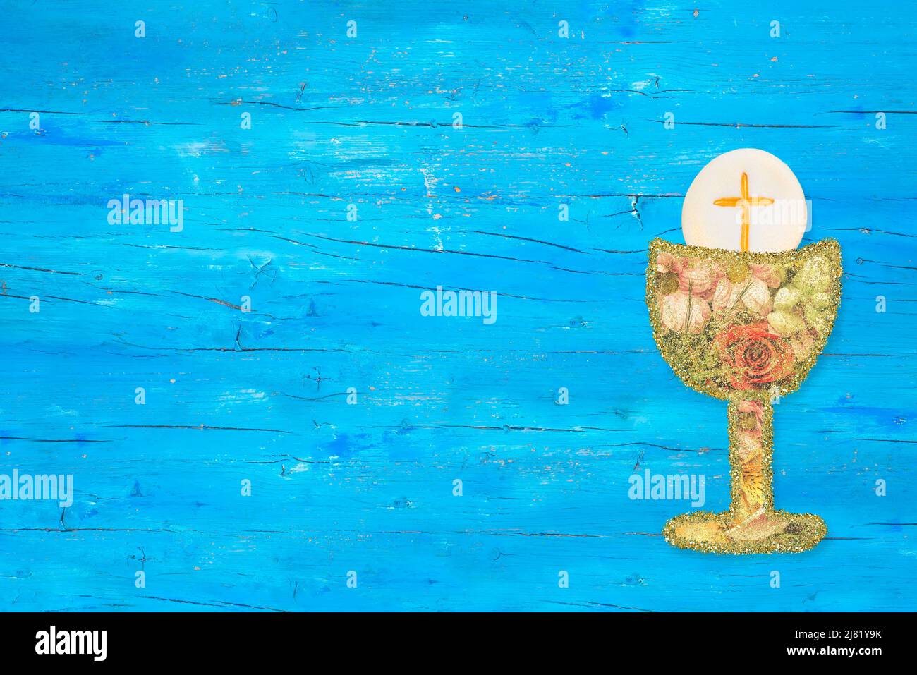 Carte d'invitation première communion sainte. Fleurs et calice d'or sur fond bleu en bois avec espace de copie pour le texte et la photo. Banque D'Images
