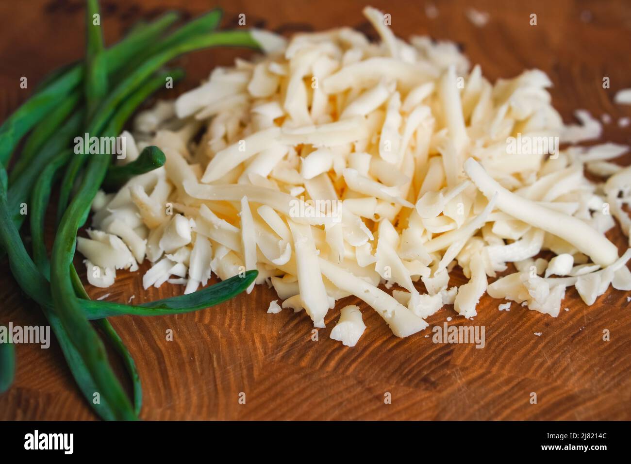 Plumes d'oignon vert et fromage haché sur bois. Ingrédients pour la salade Banque D'Images