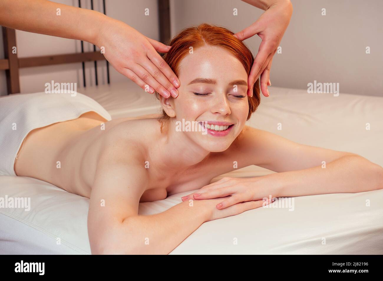 au spa, une femme au gingembre aux cheveux rouges reçoit un massage du visage Banque D'Images