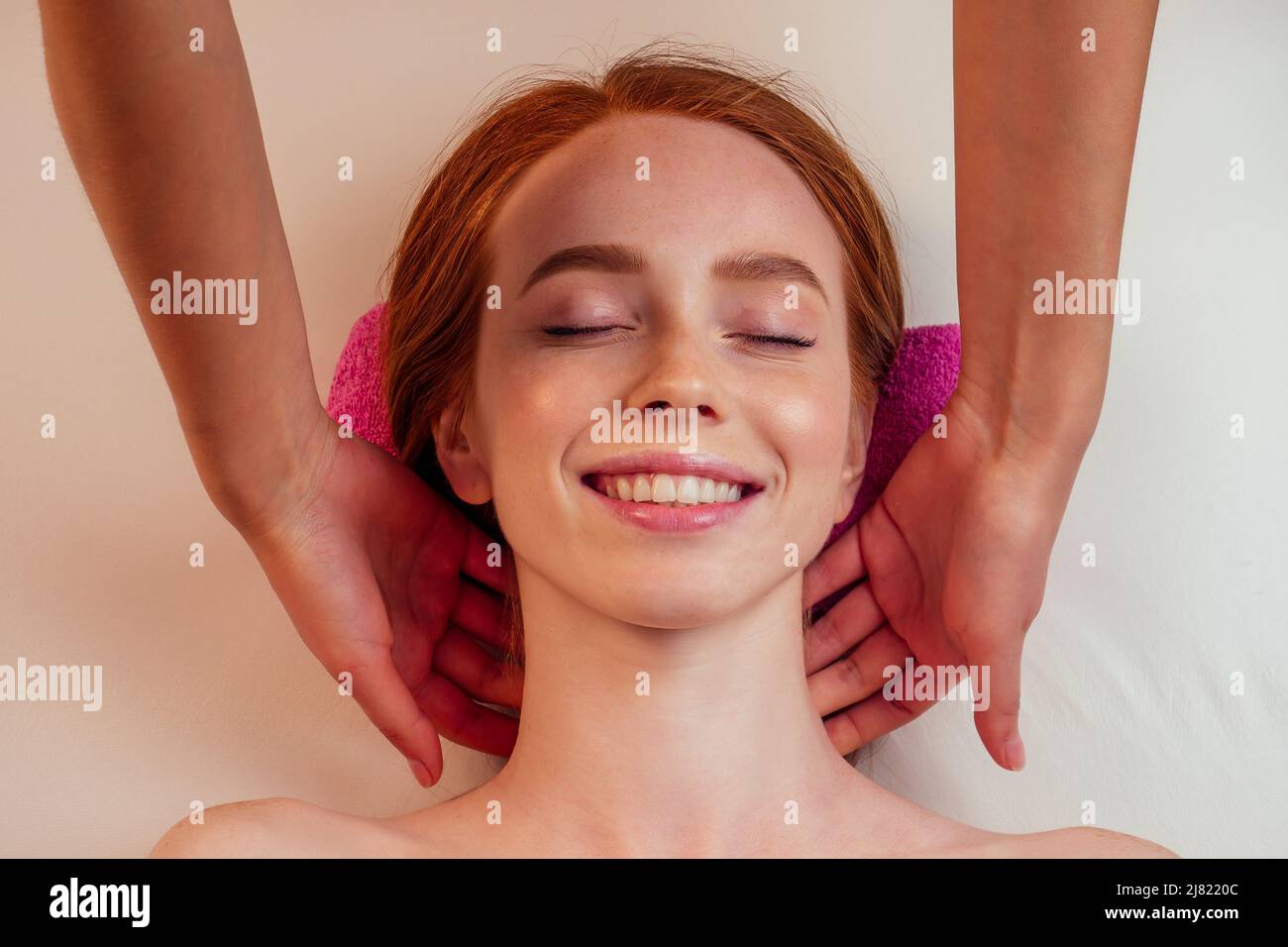 au spa, une femme au gingembre aux cheveux rouges reçoit un massage du visage Banque D'Images