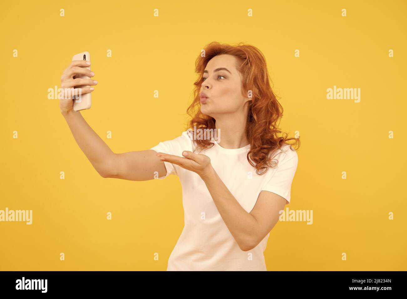 Gadget accro.Selfie fille blogger fond jaune.Femme donne la main embrassant au smartphone Banque D'Images