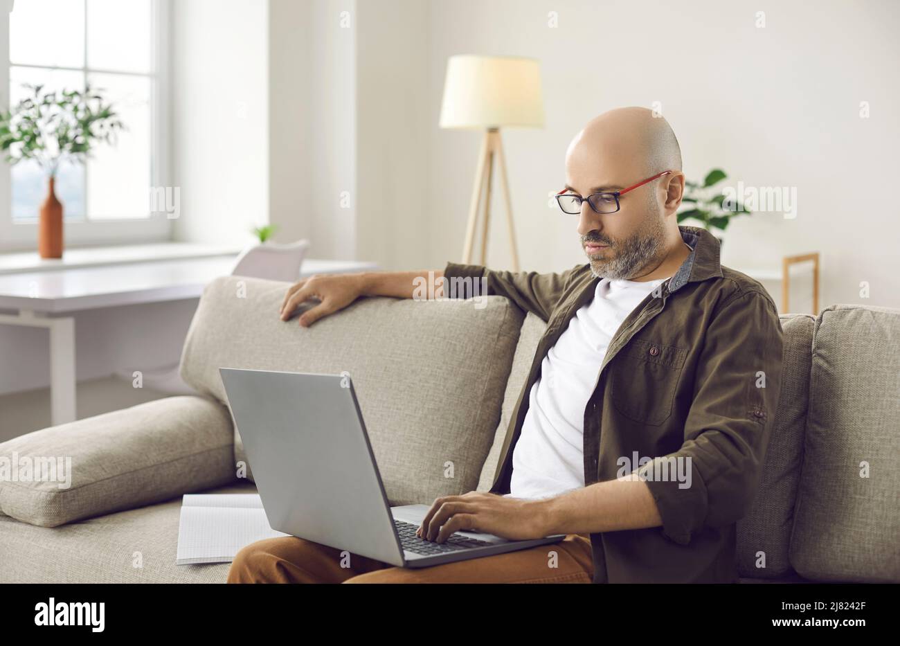 Un homme d'âge moyen travaille en ligne sur un ordinateur à la maison Banque D'Images
