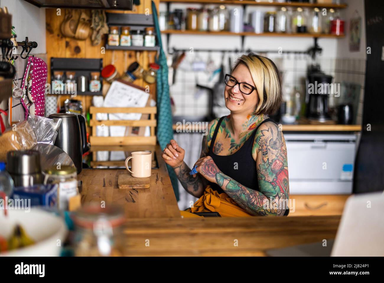 Portrait d'une jeune femme tatouée en fauteuil roulant à la maison Banque D'Images