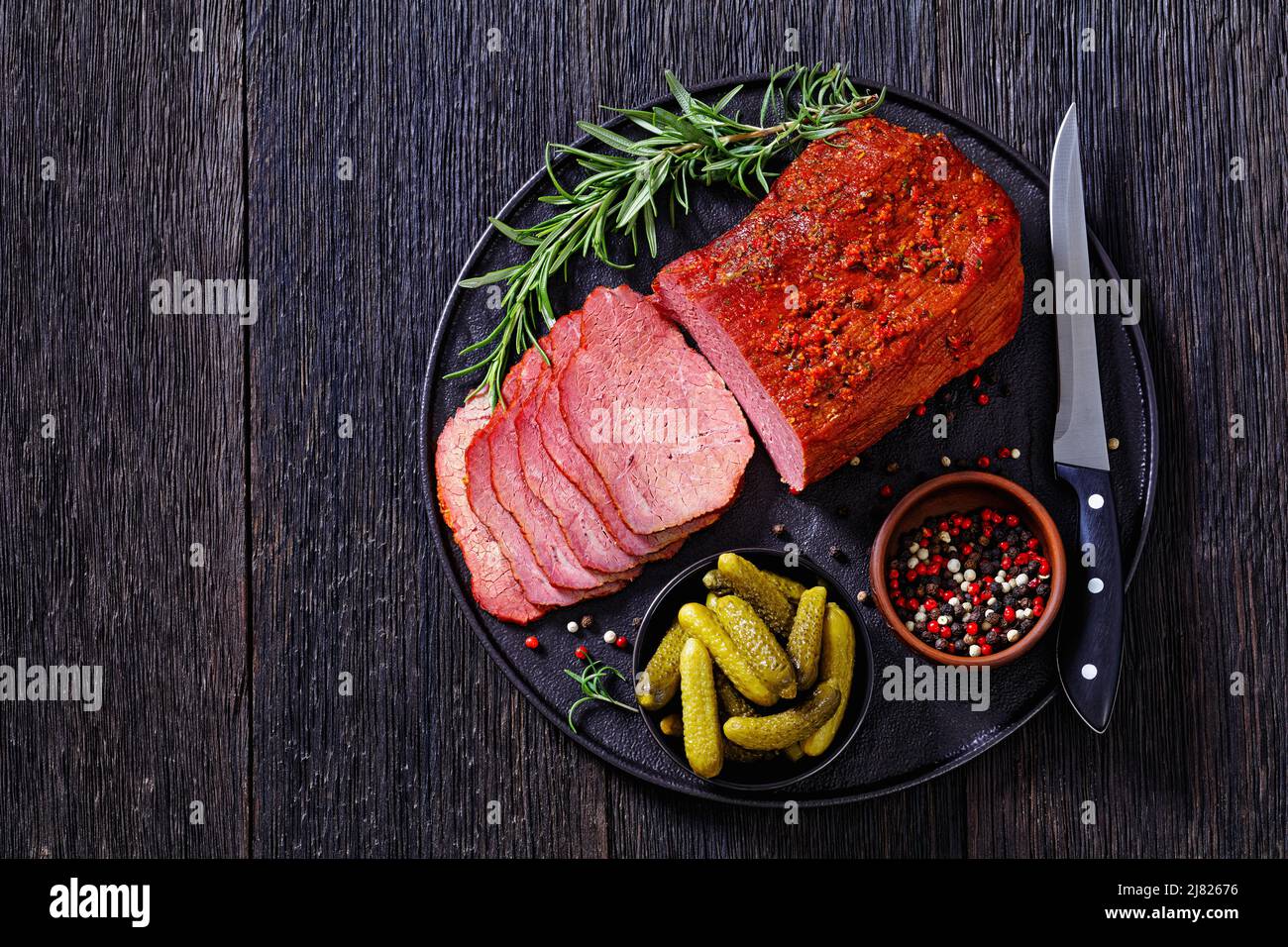 pastrami de bœuf frais tranché sur une assiette noire avec romarin