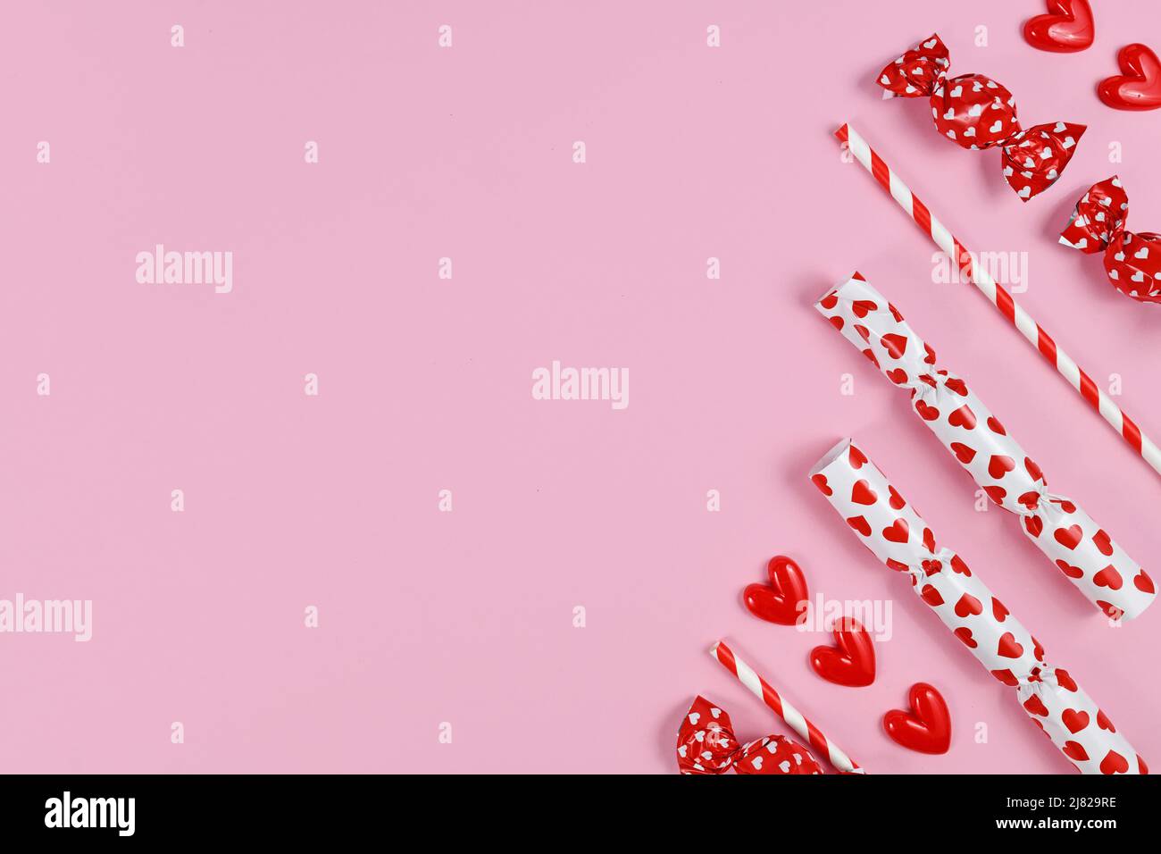 Bonbon rouge et blanc avec emballage avec coeurs sur fond rose Banque D'Images
