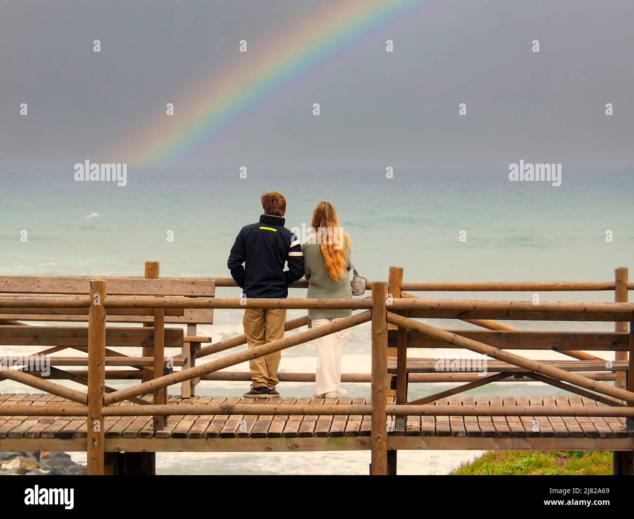 Un couple hétérosexuel contemplant un arc-en-ciel en face de la plage de Marbella Banque D'Images