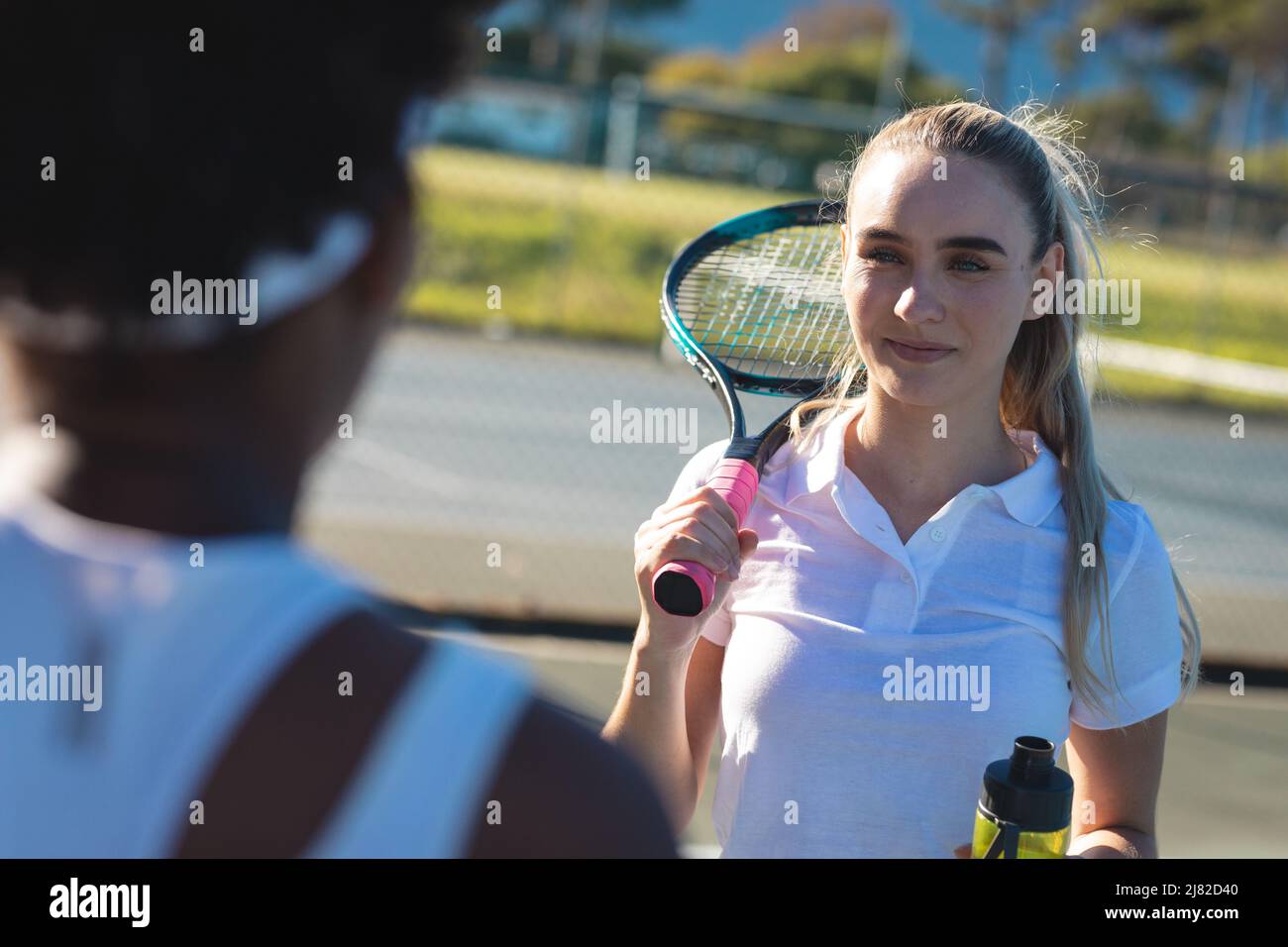 Souriant belle jeune femme caucasienne regardant l'athlète afro-américain sur le court de tennis Banque D'Images