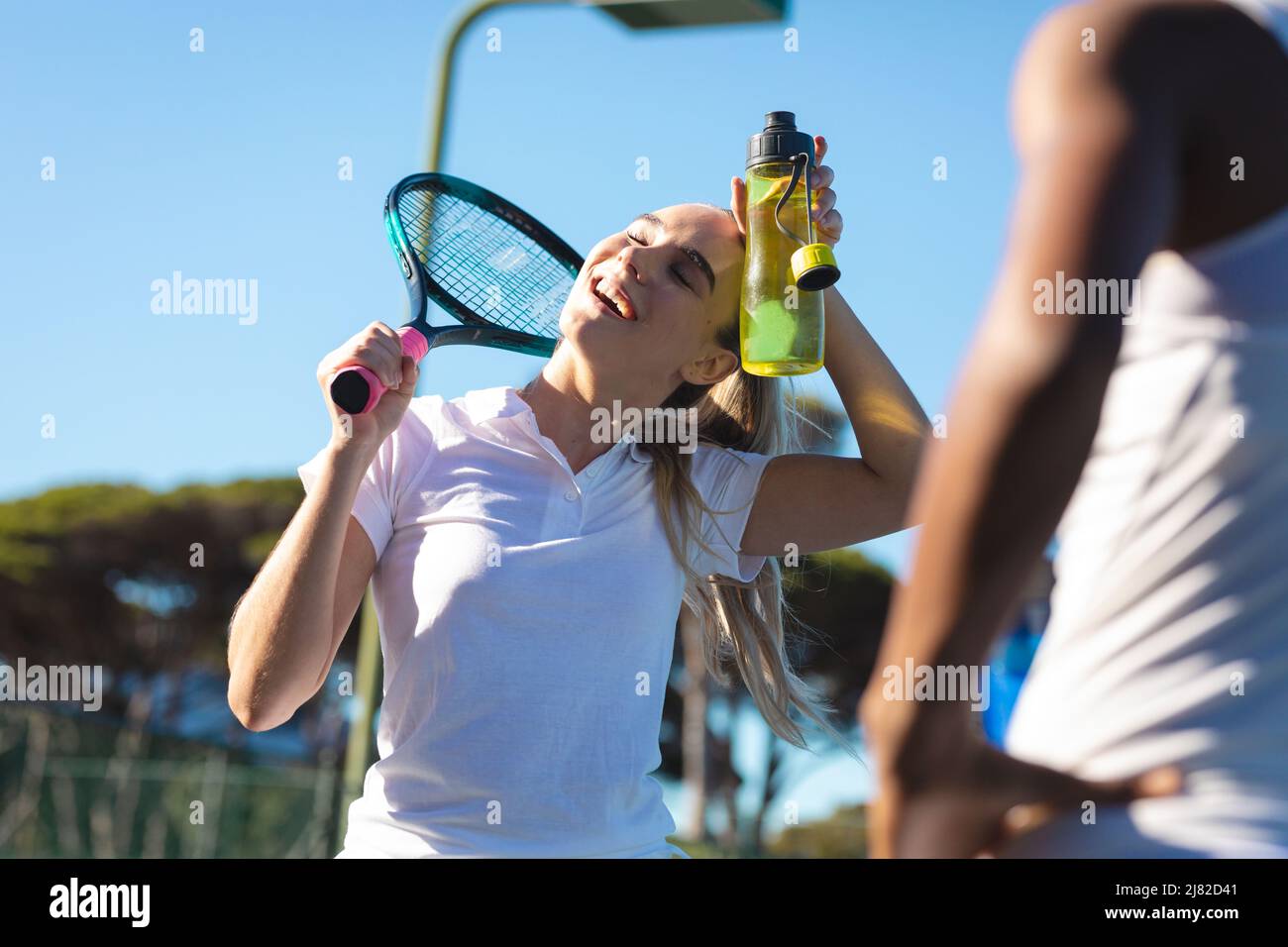 Femme caucasienne souriante tenant la sueur de nettoyage de bouteille par l'athlète sur le terrain Banque D'Images