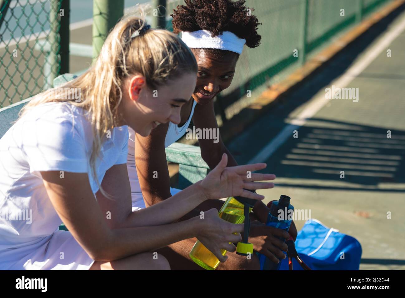 Des joueuses de tennis multiraciales se font une pause tout en parlant sur le court par beau temps Banque D'Images