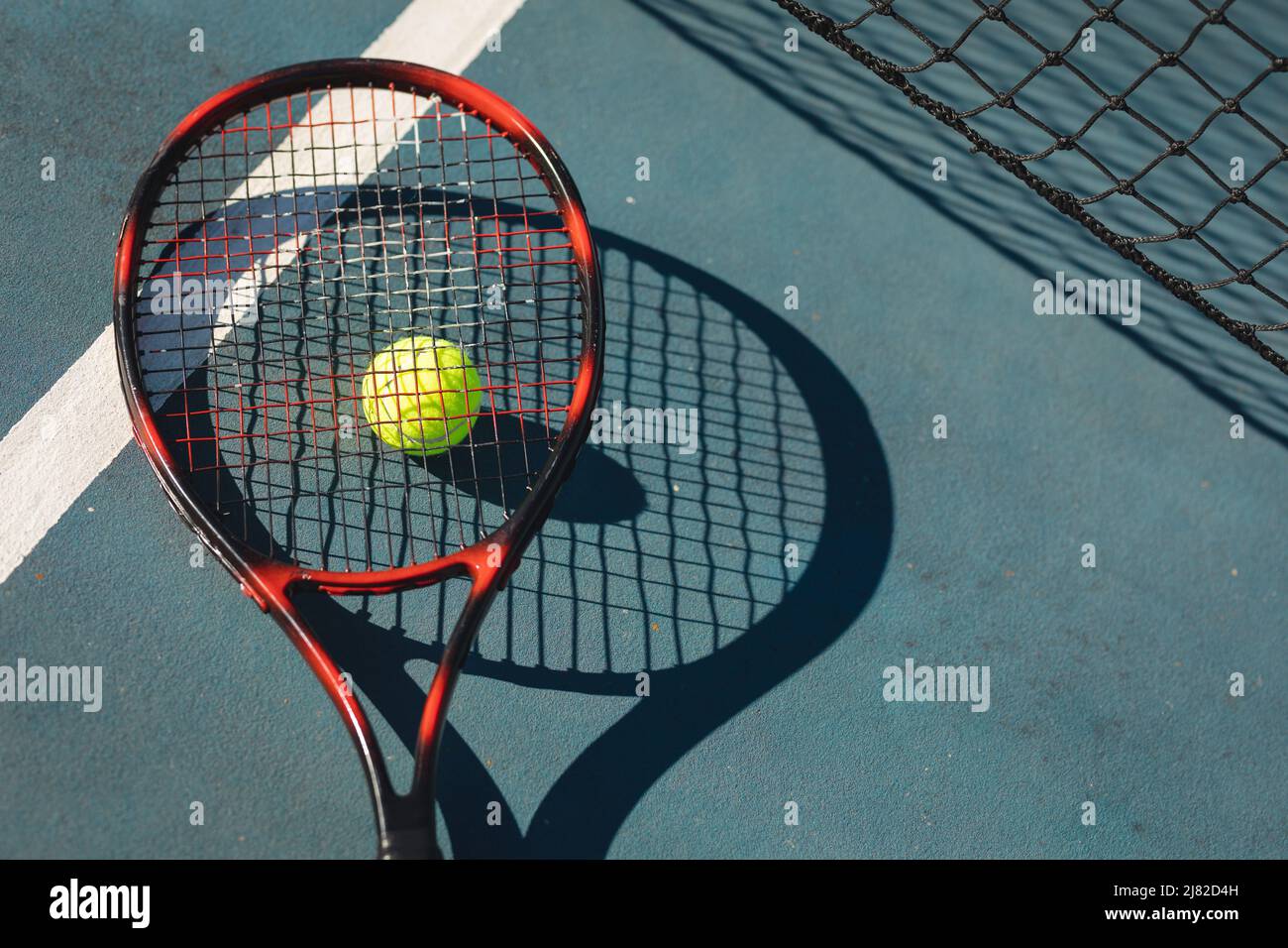 Vue en hauteur de la raquette de tennis rouge sur le ballon et le court avec ligne pendant la journée ensoleillée Banque D'Images