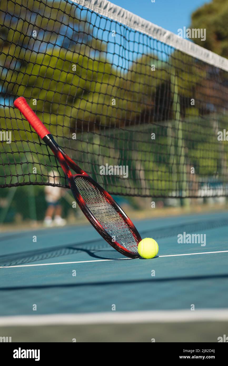 Vue au niveau de la surface du ballon par une raquette penchée sur le filet de tennis sur le court pendant la journée ensoleillée Banque D'Images