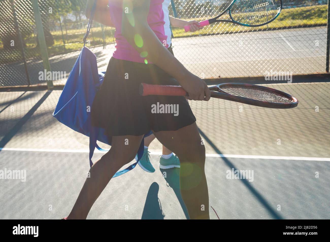 Section médiane d'une joueuse de tennis afro-américaine marchant avec une athlète sur le terrain par beau temps Banque D'Images