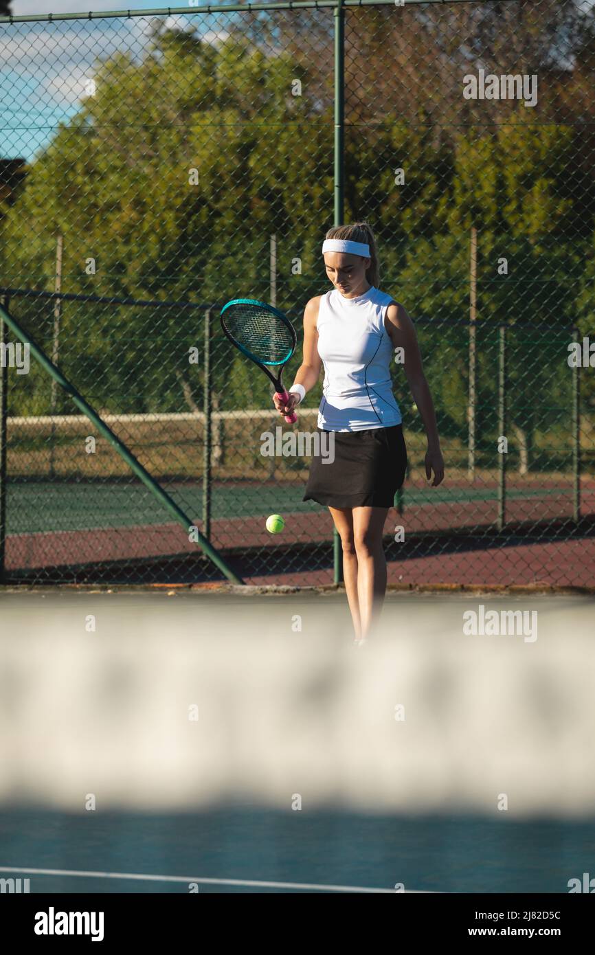 Jeune athlète caucasienne servant sur un court de tennis par beau temps Banque D'Images