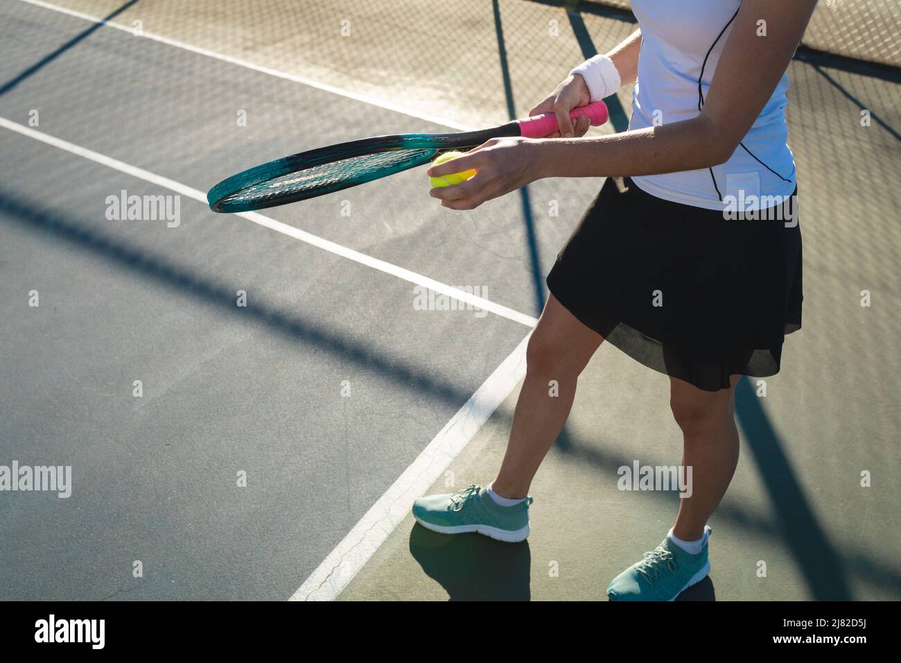 Petite section de jeunes femmes caucasiennes servant sur le court de tennis le jour ensoleillé Banque D'Images