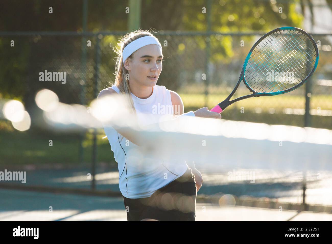Belle jeune athlète caucasienne jouant au tennis avec raquette sur le court le jour ensoleillé Banque D'Images