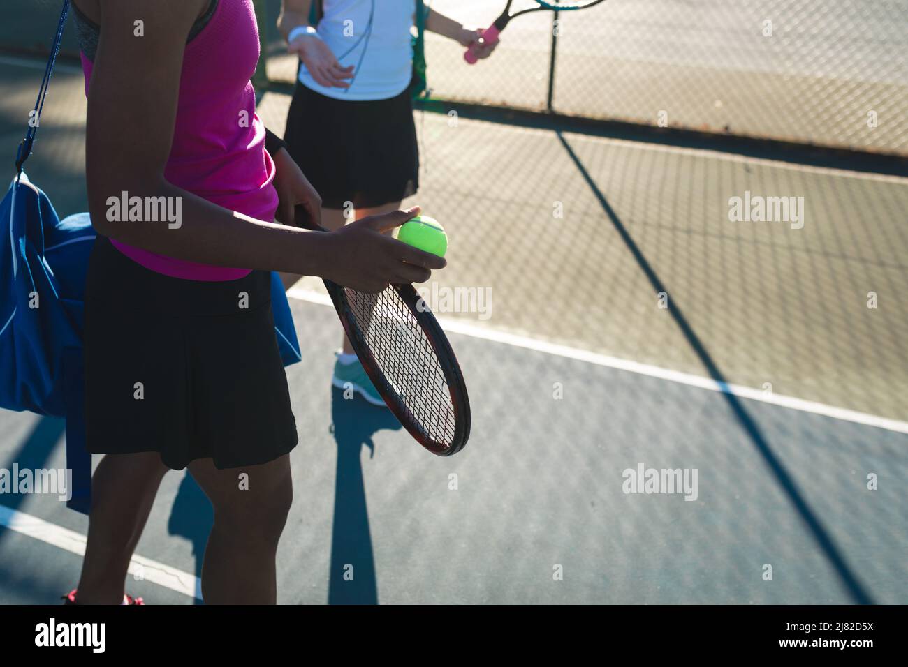 Des joueuses de tennis biraciales debout sur le terrain par beau temps Banque D'Images