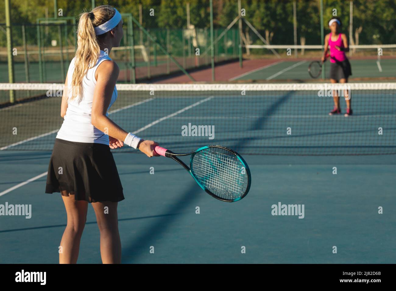 Athlète caucasienne jouant au tennis avec un joueur afro-américain sur le terrain par beau temps Banque D'Images