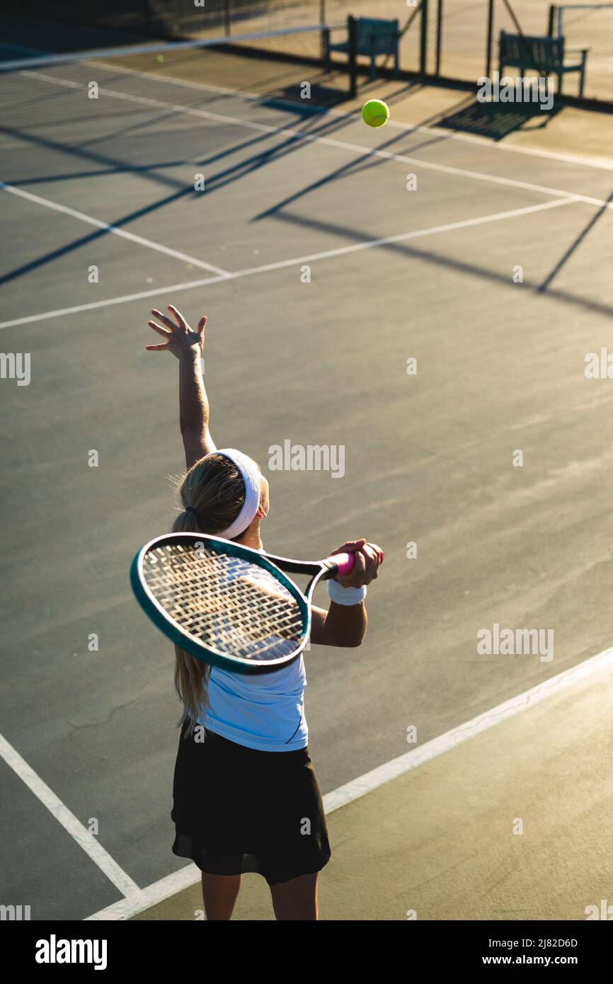 Vue en grand angle de la jeune femme de tennis caucasien servant pendant le match sur le terrain Banque D'Images