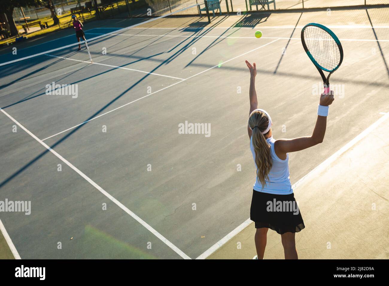 Vue en grand angle du jeune joueur de tennis caucasien servant pendant le match sur le terrain Banque D'Images