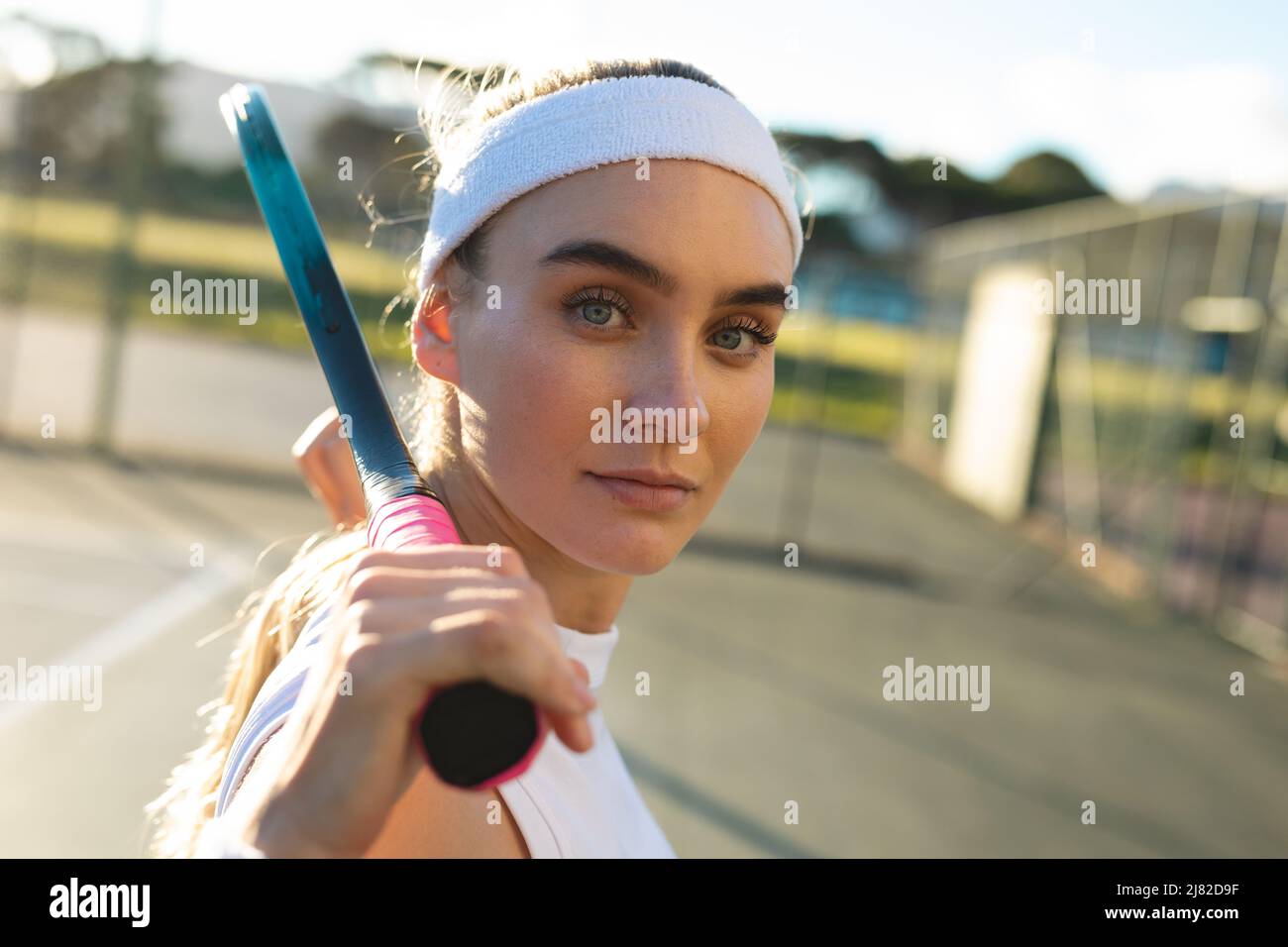 Vue latérale portrait d'une jeune femme de tennis caucasienne très confiante debout avec une raquette Banque D'Images