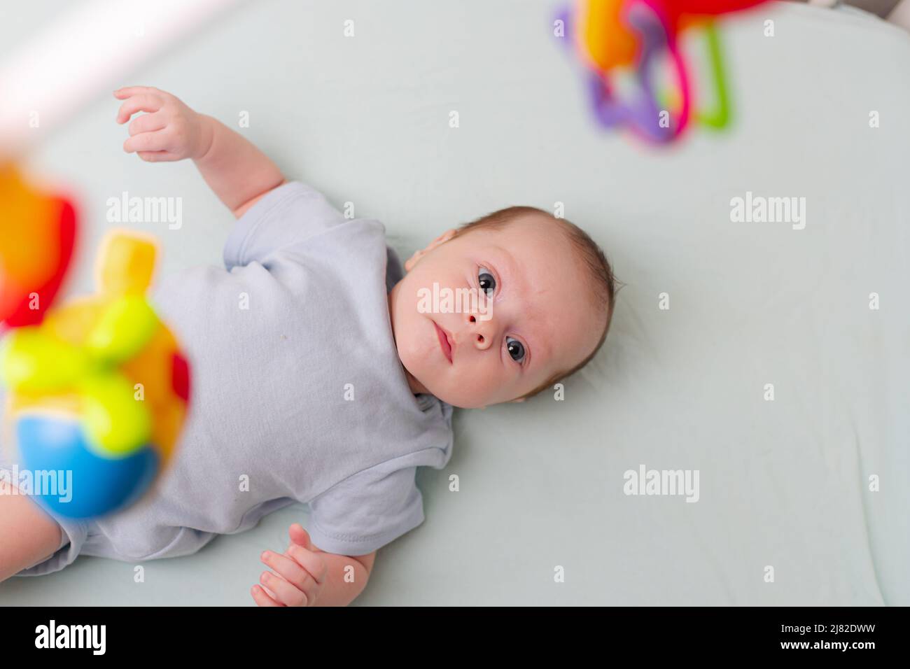 Le bébé regarde le mobile couché dans le berceau . Mobile au lit de bébé. Un article sur les loisirs pour enfants. Les mains de maman sont libres. Un article sur le choix d'un mobile dans le berceau. Le bébé a 0-3 mois. Un bébé Banque D'Images