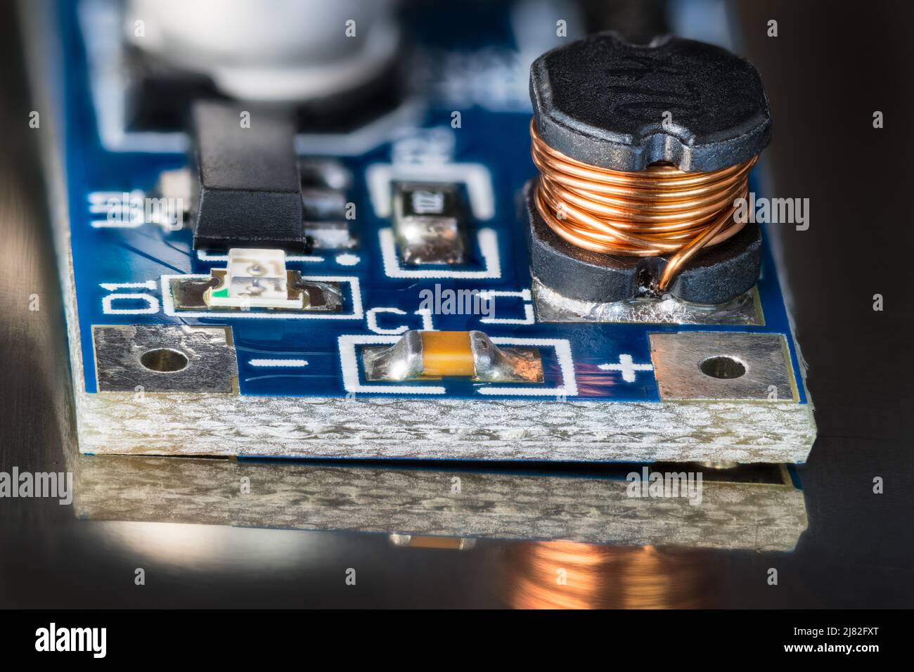 Bobine électronique, module de convertisseur CC-CC noir, diode LED ou condensateur sur détail PCB bleu avec réflexion sur fond noir brillant. Carte de circuit imprimé CMS. Banque D'Images