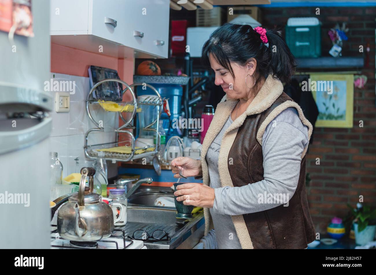 Femme adulte caucasienne souriant debout dans la cuisine à la maison pour préparer le petit déjeuner. Banque D'Images