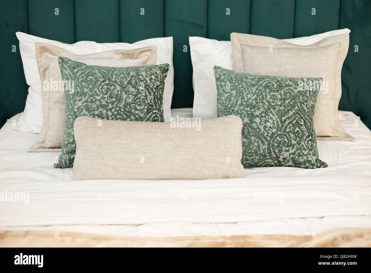 Lit avec tête de lit en velours vert doux et oreillers dans les tons de beige et de vert avec un motif. Gros plan Banque D'Images