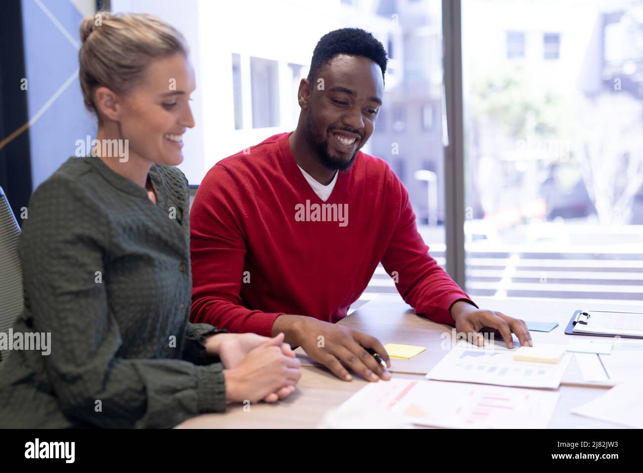 Homme d'affaires et femme d'affaires souriants discutant des documents dans la salle de réunion sur le lieu de travail Banque D'Images