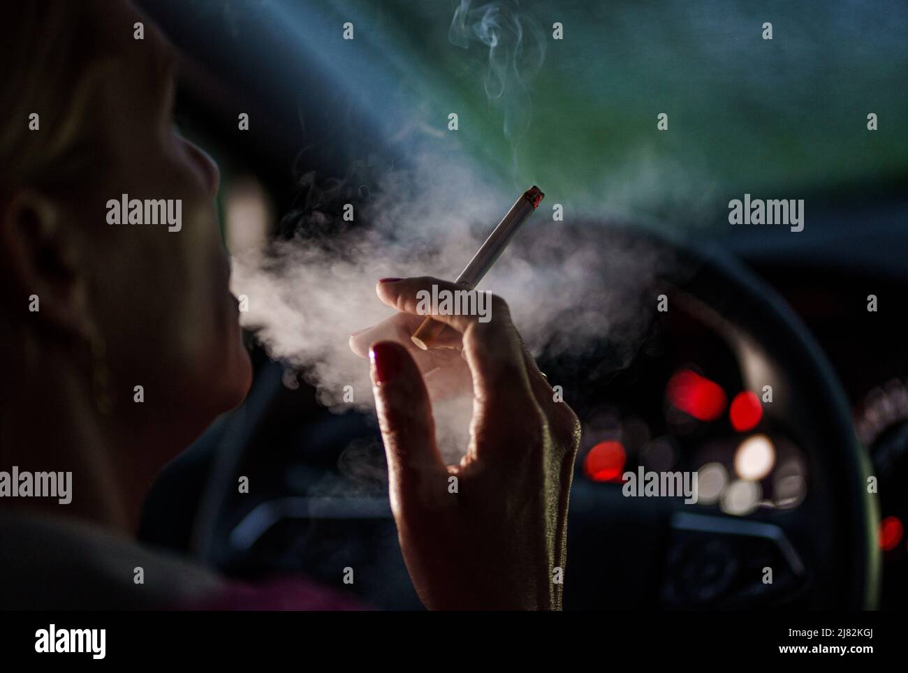 11 mai 2022, Schleswig-Holstein, Flensburg: Une femme est assise derrière le volant de sa voiture avec une cigarette allumée. Photo: Axel Heimken/dpa Banque D'Images