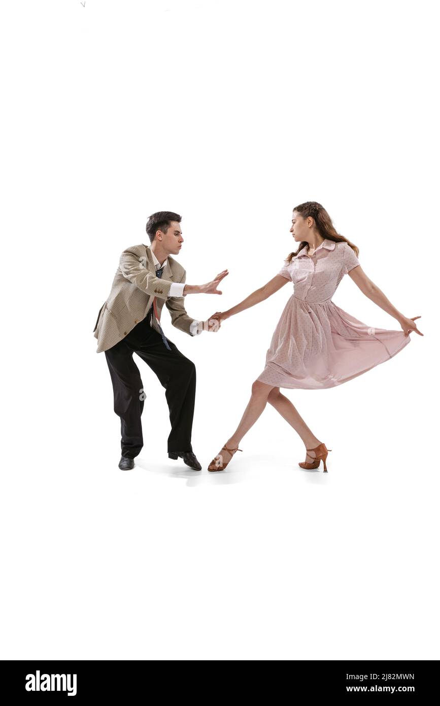 Jeune homme et femme en costume rétro vintage dansant danse sociale isolée sur fond blanc. Traditions intemporelles, 1960s mode américain Banque D'Images