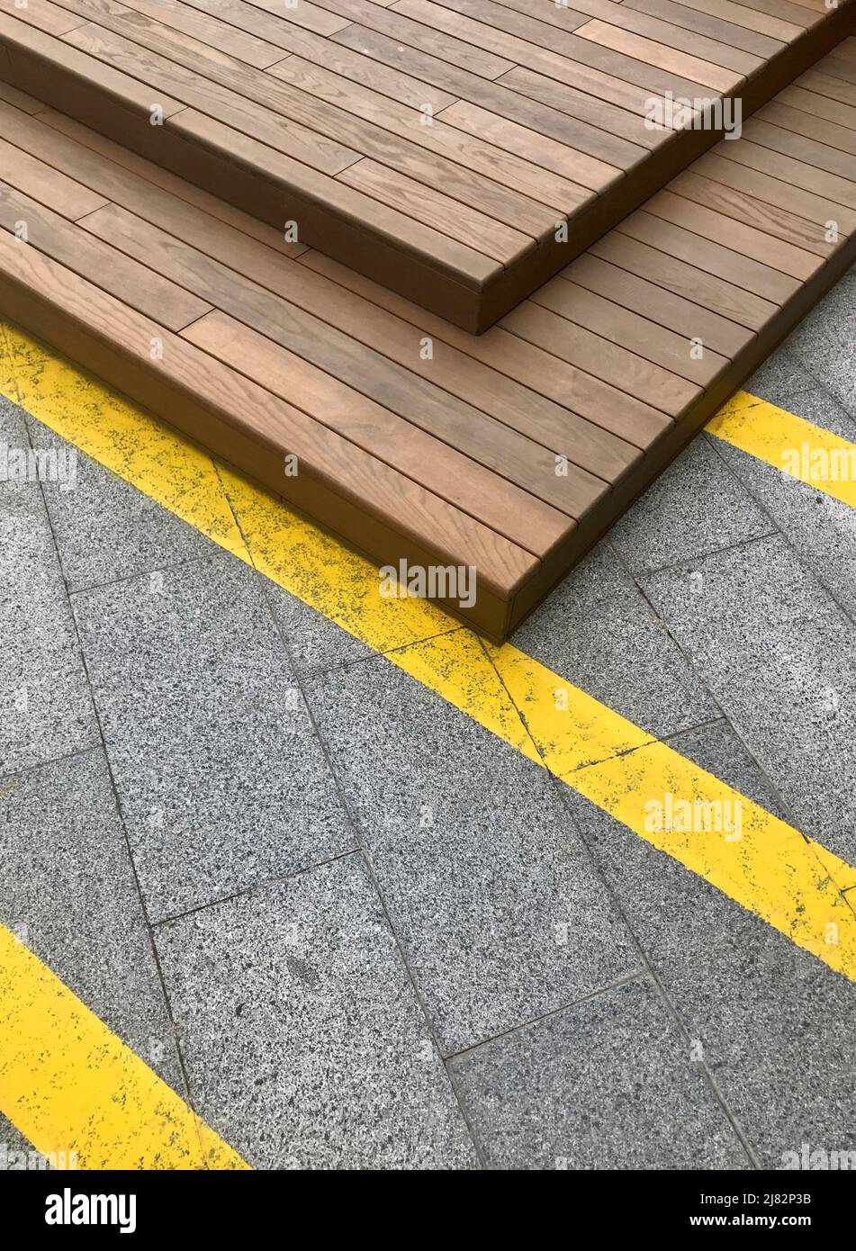 Fond géométrique urbain moderne avec lignes jaunes sur carreaux de béton et construction en bois. Banque D'Images