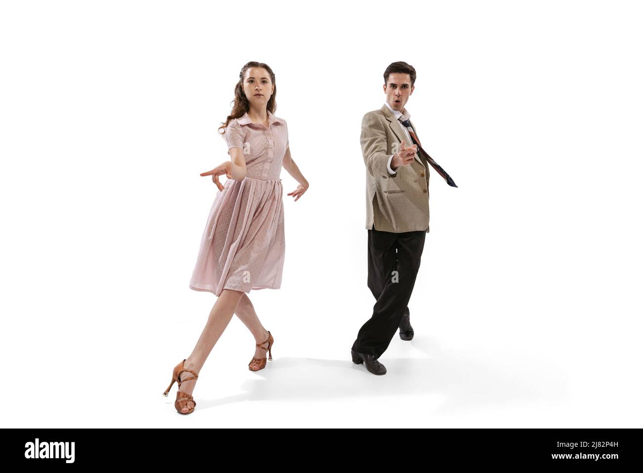 Jeune homme et femme en costume rétro vintage dansant danse sociale isolée sur fond blanc. Traditions intemporelles, 1960s mode américain Banque D'Images