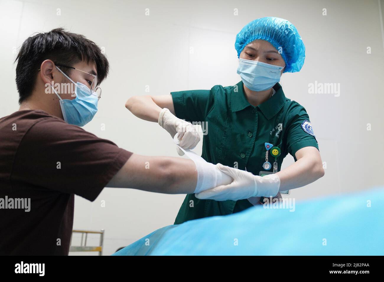 Pékin, Chine. 12th mai 2022. Une infirmière bandage la plaie pour un patient dans un hôpital du district de Beibei, dans le sud-ouest de la Chine à Chongqing, le 12 mai 2022. Le nombre d'infirmières autorisées en Chine a augmenté avec un taux annuel moyen de 8 pour cent au cours des 10 dernières années, atteignant 5,02 millions à la fin de 2021, a déclaré la Commission nationale de la santé mercredi, avant la Journée internationale des infirmières, qui tombe le 12 mai. Credit: Qin Tingfu/Xinhua/Alamy Live News Banque D'Images