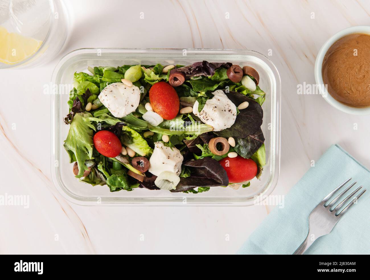 Récipient de préparation des aliments avec salade, tomate, olives mozzarella et noix de pin Banque D'Images