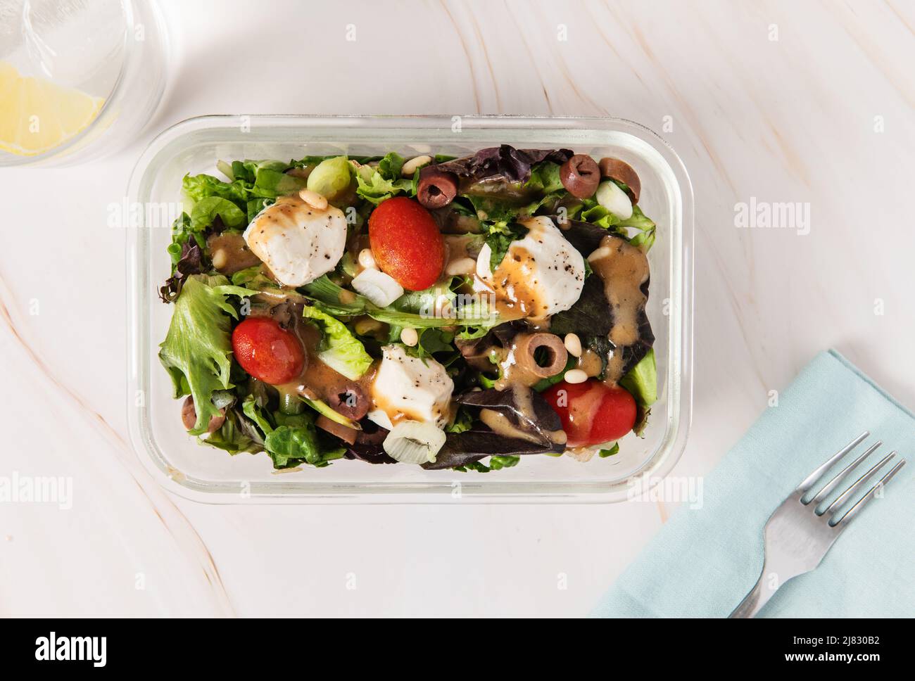 Récipient de préparation des aliments avec salade, tomate, olives mozzarella et pignons et vinaigrette Banque D'Images