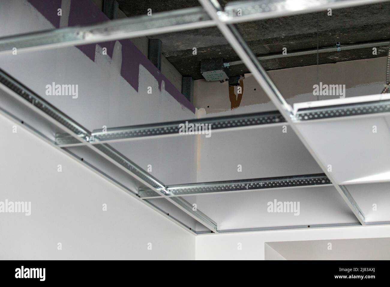 Déposer la grille de plafond installée sur une cloison sèche par un entrepreneur dans un bâtiment commercial Banque D'Images