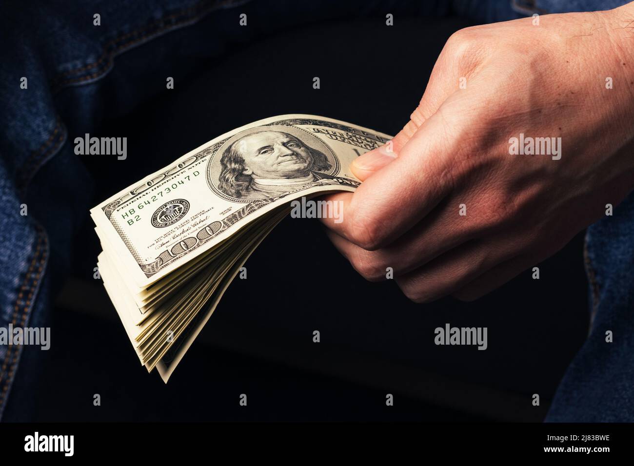 Main masculine nous tenant des billets de cent dollars. Un homme avec de l'argent américain en gros plan Banque D'Images