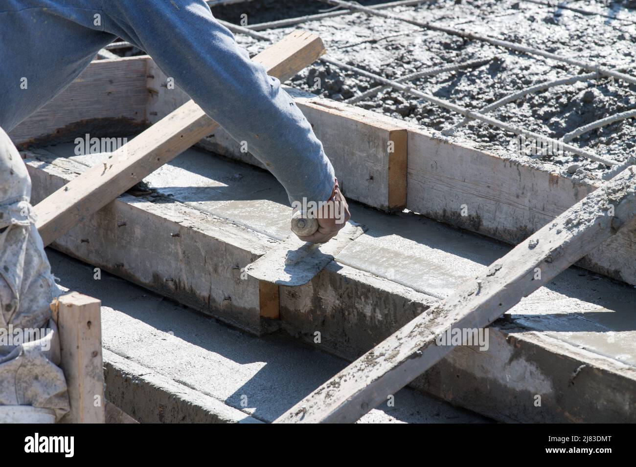 Travailleur de la construction utilisant une truelle de finition pour lisser les marches ou escaliers en béton fraîchement coulées sur un nouveau bâtiment résidentiel. Banque D'Images