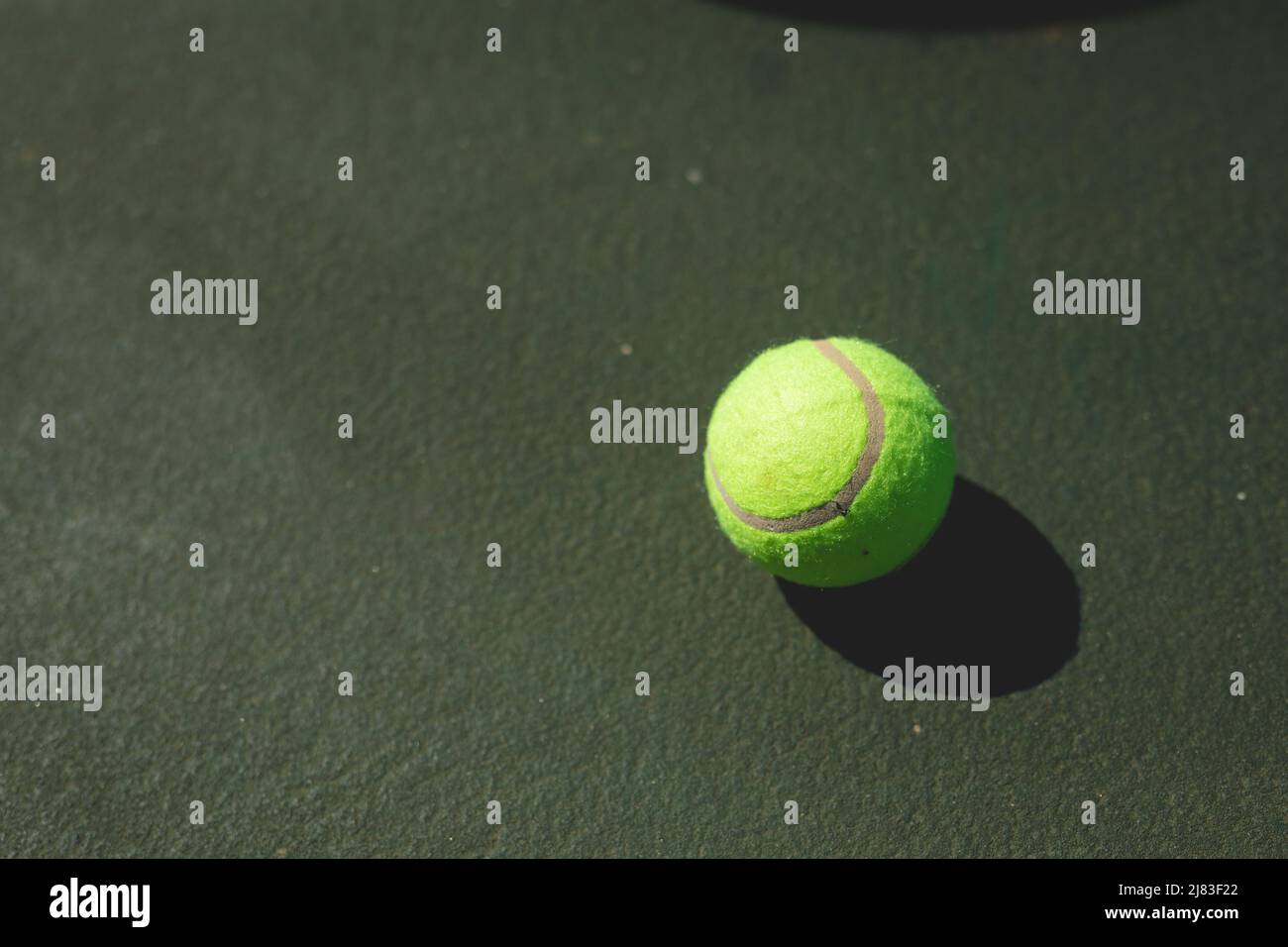 Juste au-dessus de la vue du ballon de tennis vert avec ombre sur le terrain gris pendant la journée ensoleillée Banque D'Images